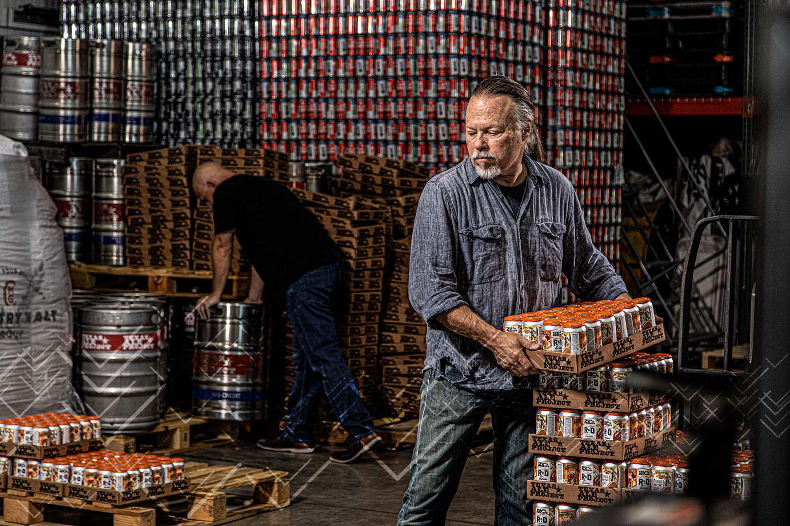 middle aged warehouse worker lifting case of texas ale beer in warehouse at distribution center